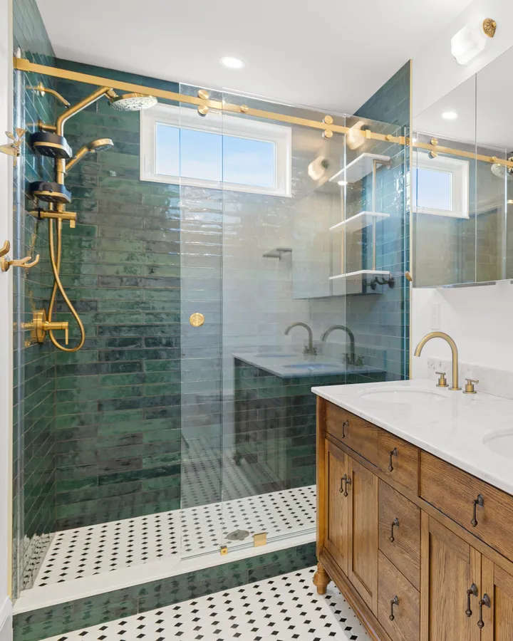 After: the primary bath, a green tile shower behind frameless glass and a double vanity